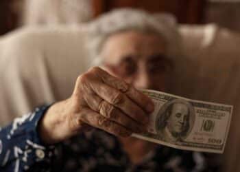 Elderly woman holding a $100 bill as part of the $900 heating assistance program in New York, 2025