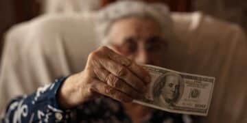 Elderly woman holding a $100 bill as part of the $900 heating assistance program in New York, 2025