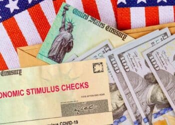 IRS economic stimulus check next to $100 bills and the US flag