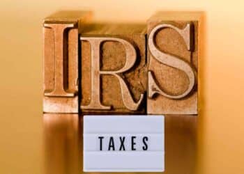 Wooden blocks with the letters 'IRS' and a sign with the word 'Taxes', representing taxes in the USA