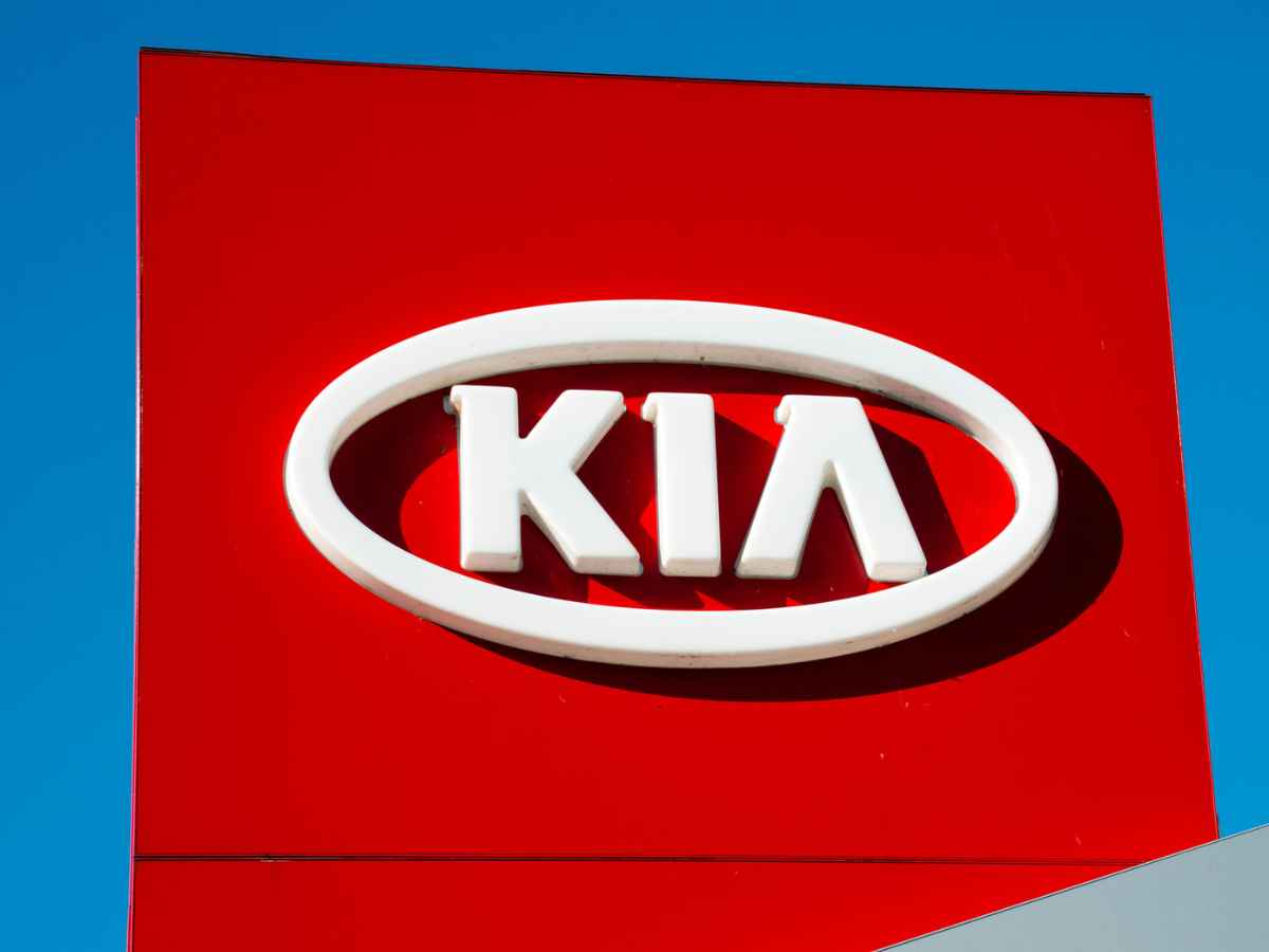 Kia logo on a red dealership sign against a clear blue sky