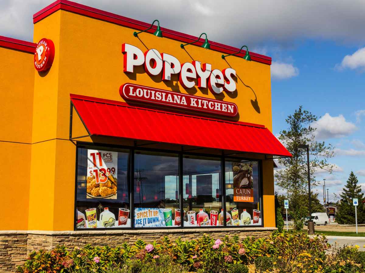 Bright exterior of a Popeyes Louisiana Kitchen in Palm Coast, Florida, tied to alleged $311 credit-card fraud for inmate commissary