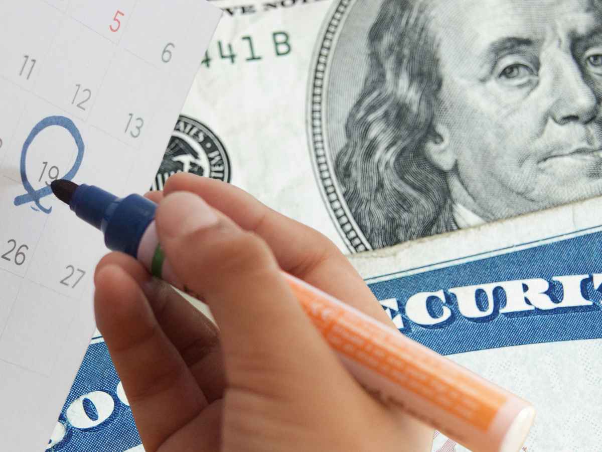 Hand circling calendar date with Social Security check and U.S. currency in background, symbolizing May 2025 payment delay