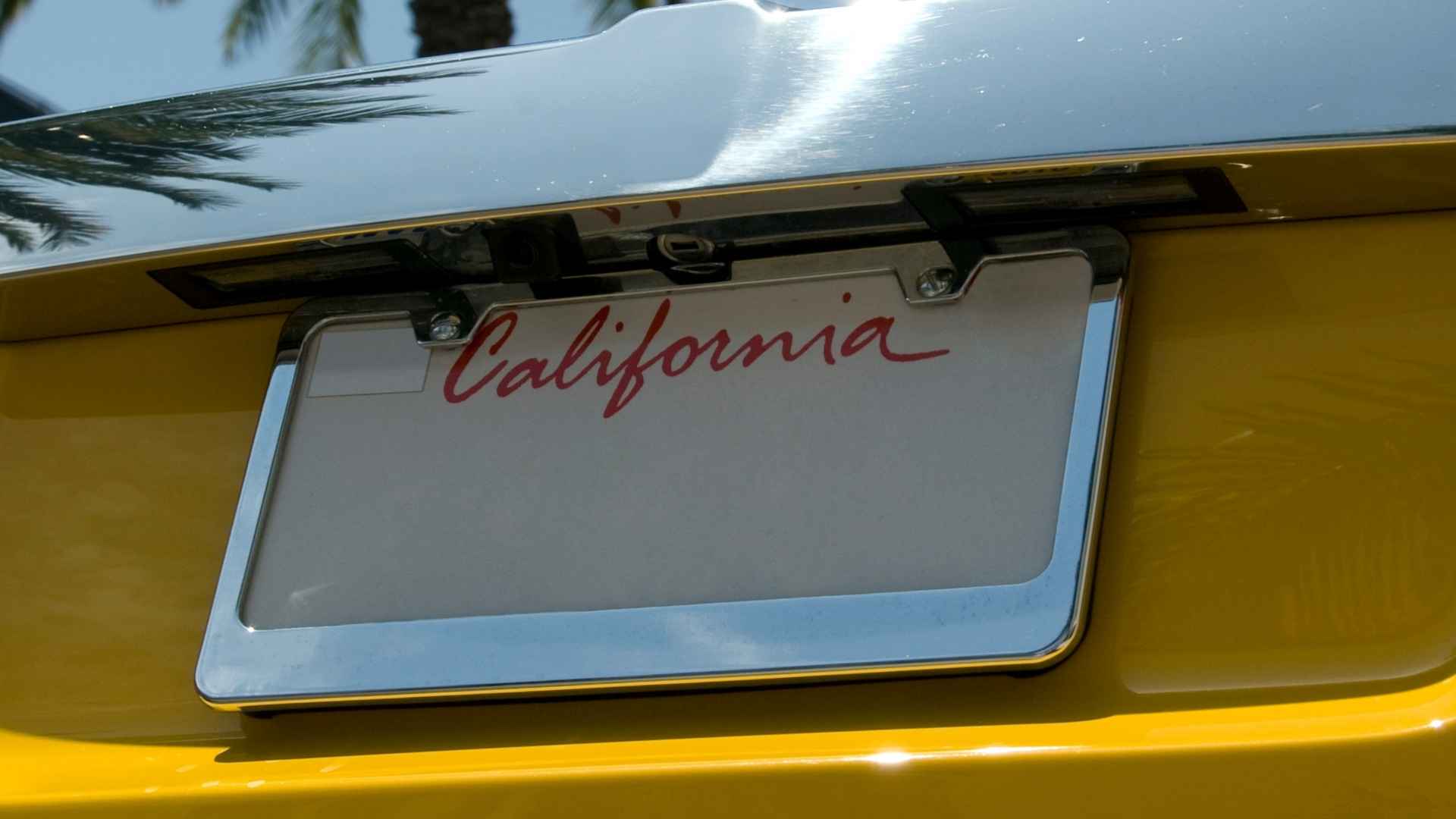Blank California license plate mounted on the rear of a yellow car bumper