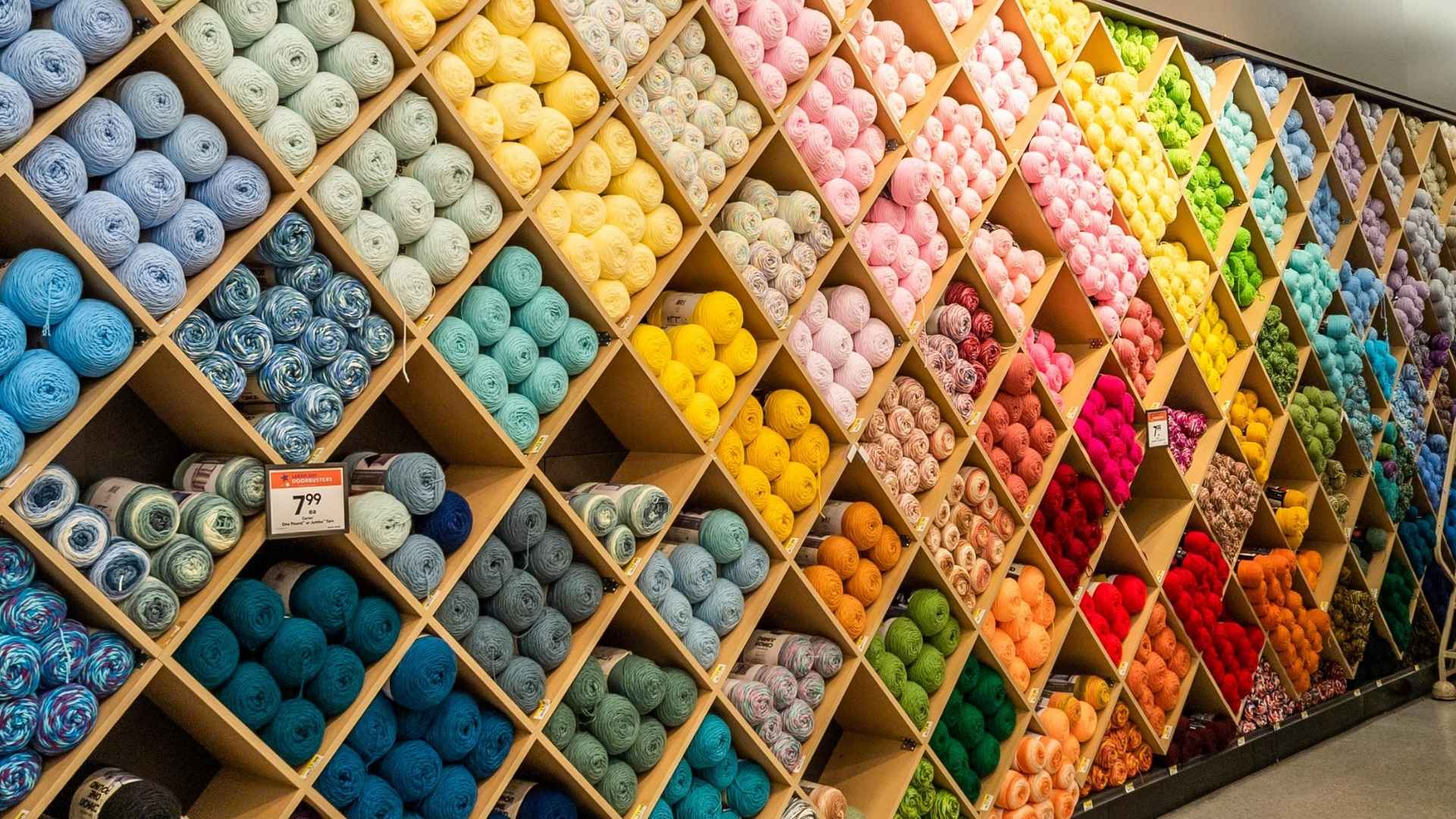 Colorful yarn skeins on diagonal shelves inside a Joann craft store ahead of nationwide closure of 500 locations in May 2025