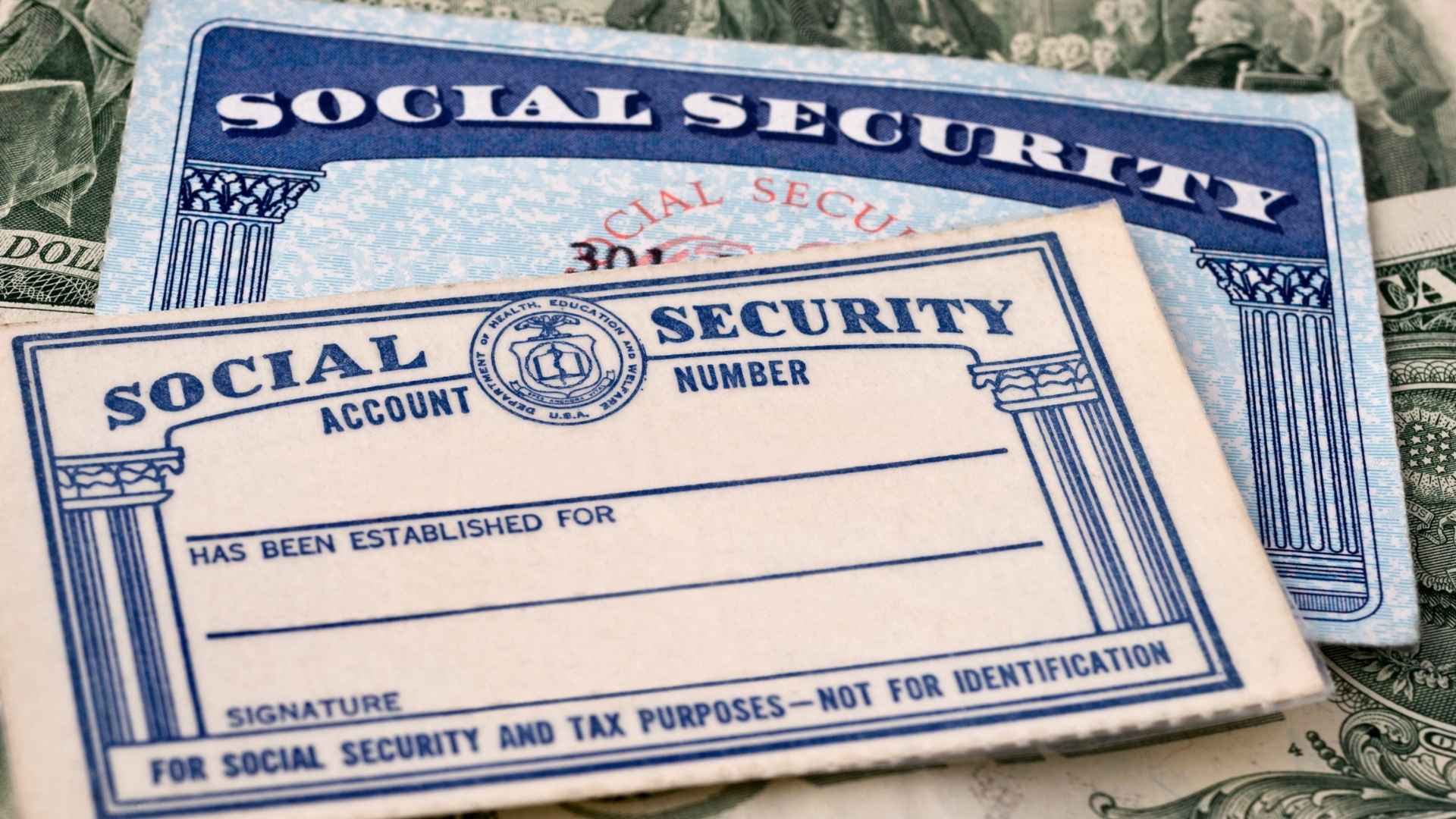 Close-up of Social Security cards on U.S. dollar bills, symbolizing immediate payment cuts that could stop May 2025 benefits for some recipients
