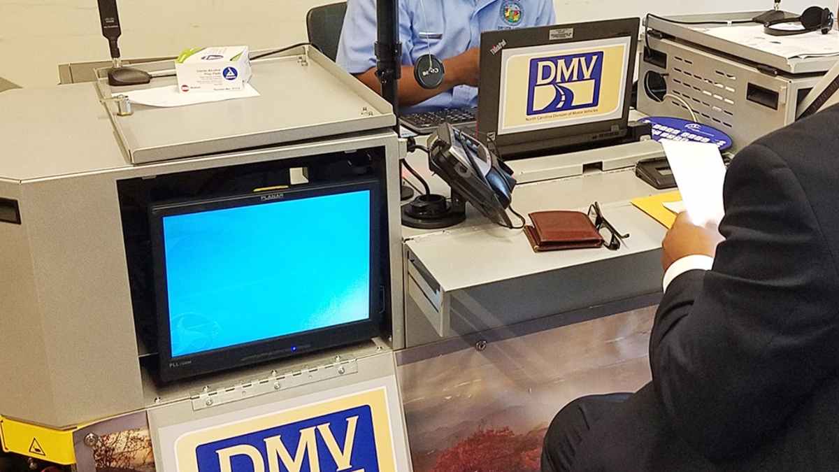North Carolina DMV desk where a clerk helps a motorist with driver’s license renewal paperwork.