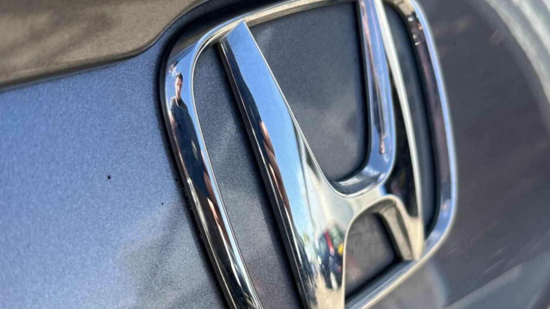 Chrome Honda badge on gray vehicle linked to NHTSA probe into idle-stop stall risk affecting 2.2 million cars