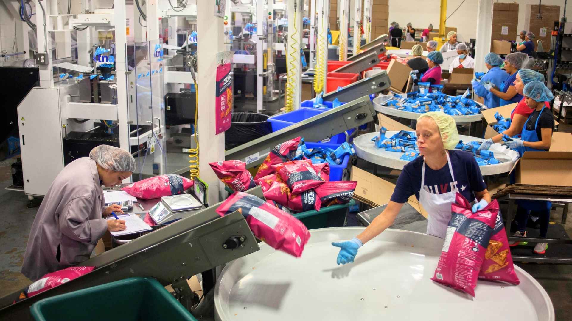 workers pack PopCorners snack bags on PepsiCo’s Liberty, NY, production line ahead of the May 2024 plant closure that will cut 300 jobs