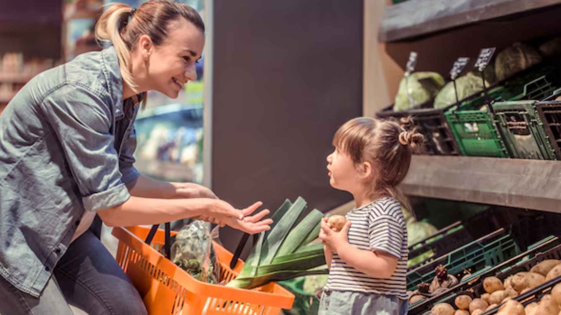 Mother and daughter pick fresh produce in grocery store, illustrating SUN Bucks $120 per-child SNAP-style summer benefit.