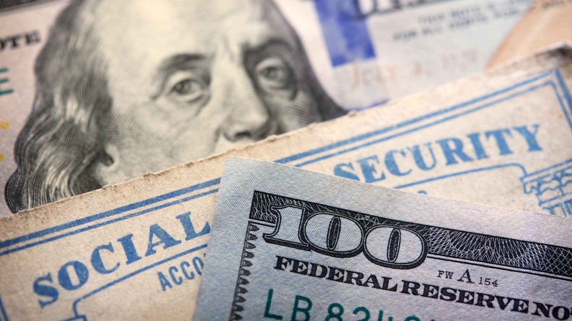 Close-up of a U.S. Social Security card and $100 bill symbolizing the 2025 retirement age chart, benefit reductions, and delay credits.