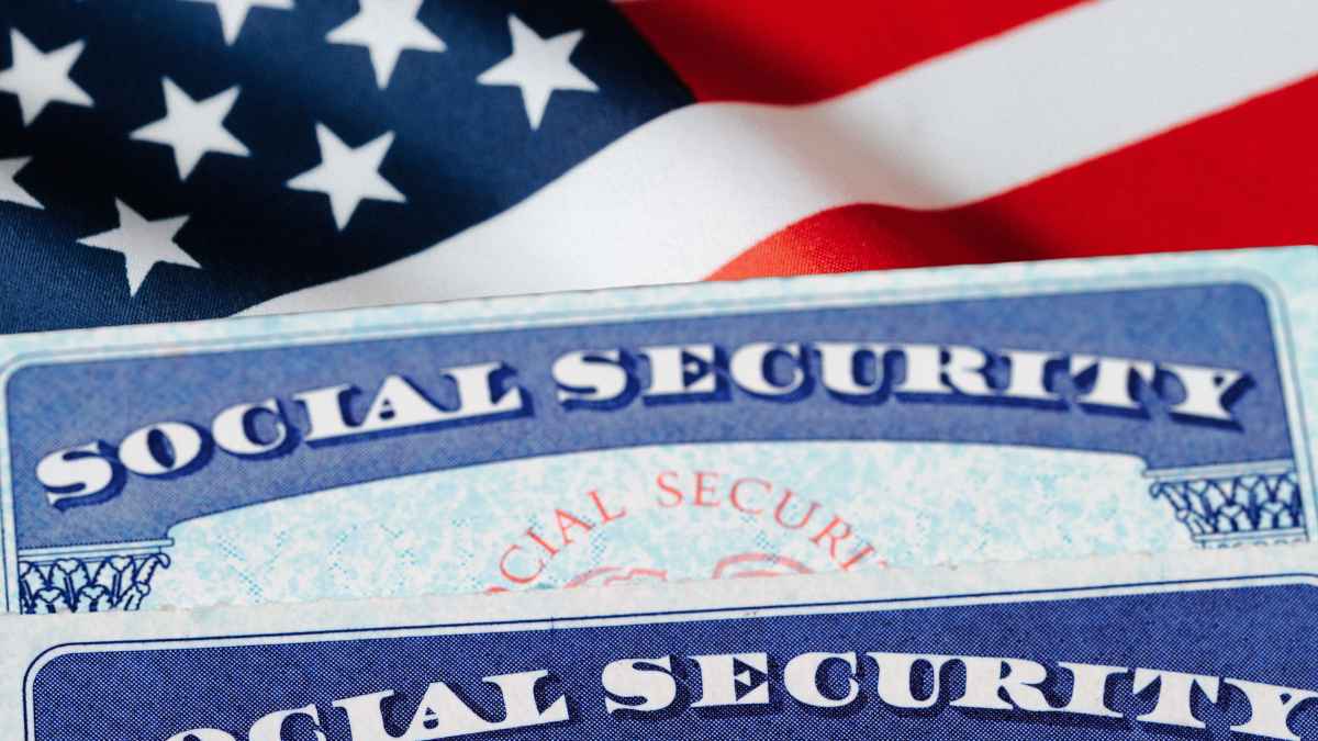 Two Social Security cards resting on a folded American flag, symbolizing U.S. retirement and disability benefits.