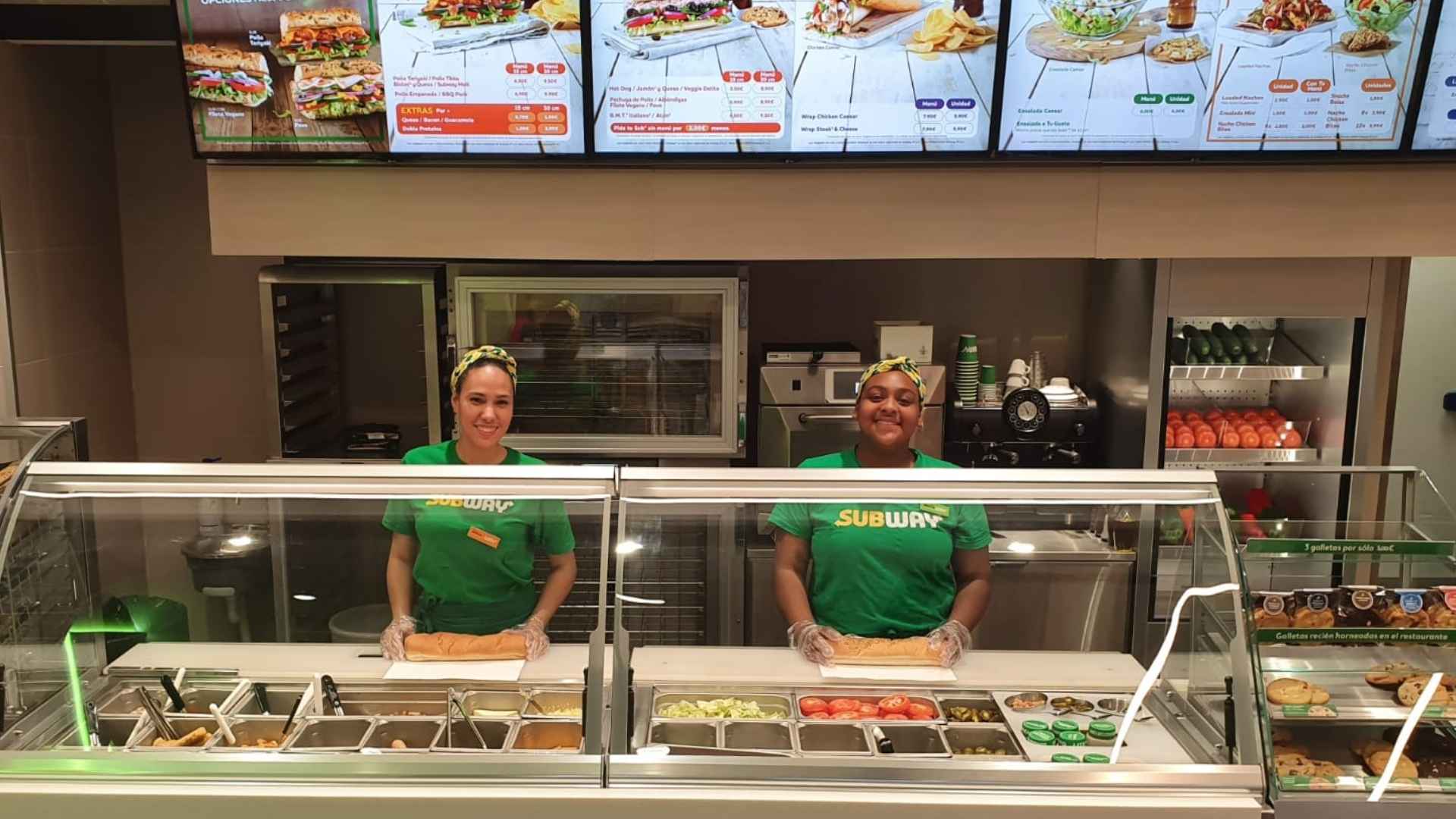 Two Subway employees prepare sandwiches behind the counter of a modern restaurant, illustrating the chain’s U.S. presence amid 631 store closures