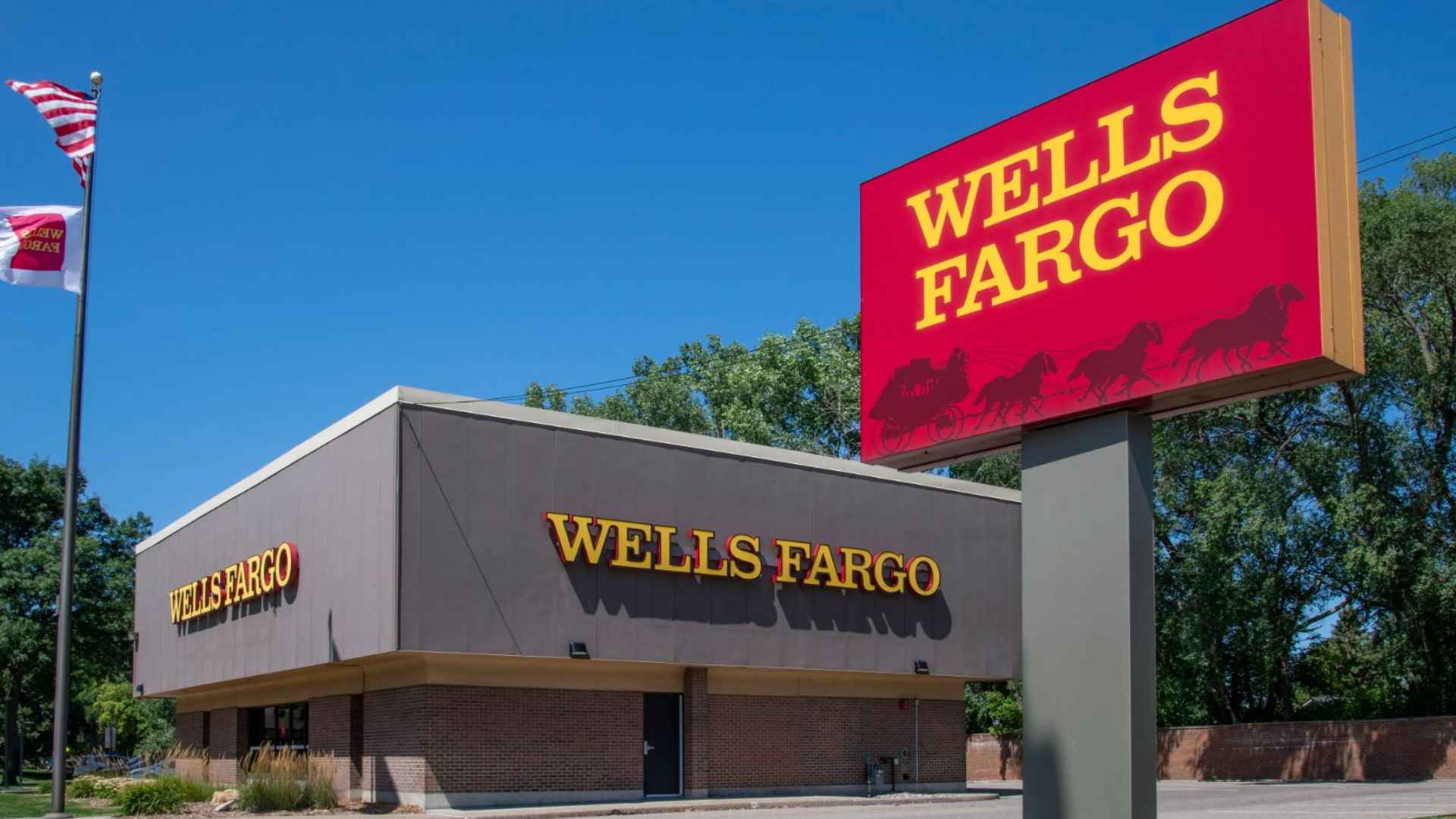 Wells Fargo branch with prominent red sign and U.S. flag, illustrating upcoming 2025 transfer-policy changes