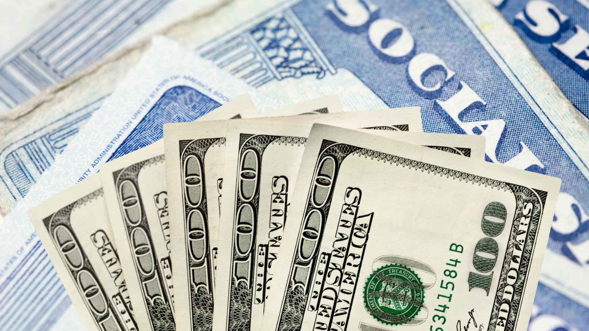 Stack of one-hundred-dollar bills on top of Social Security cards illustrating June’s 15 percent benefit garnishment plan.