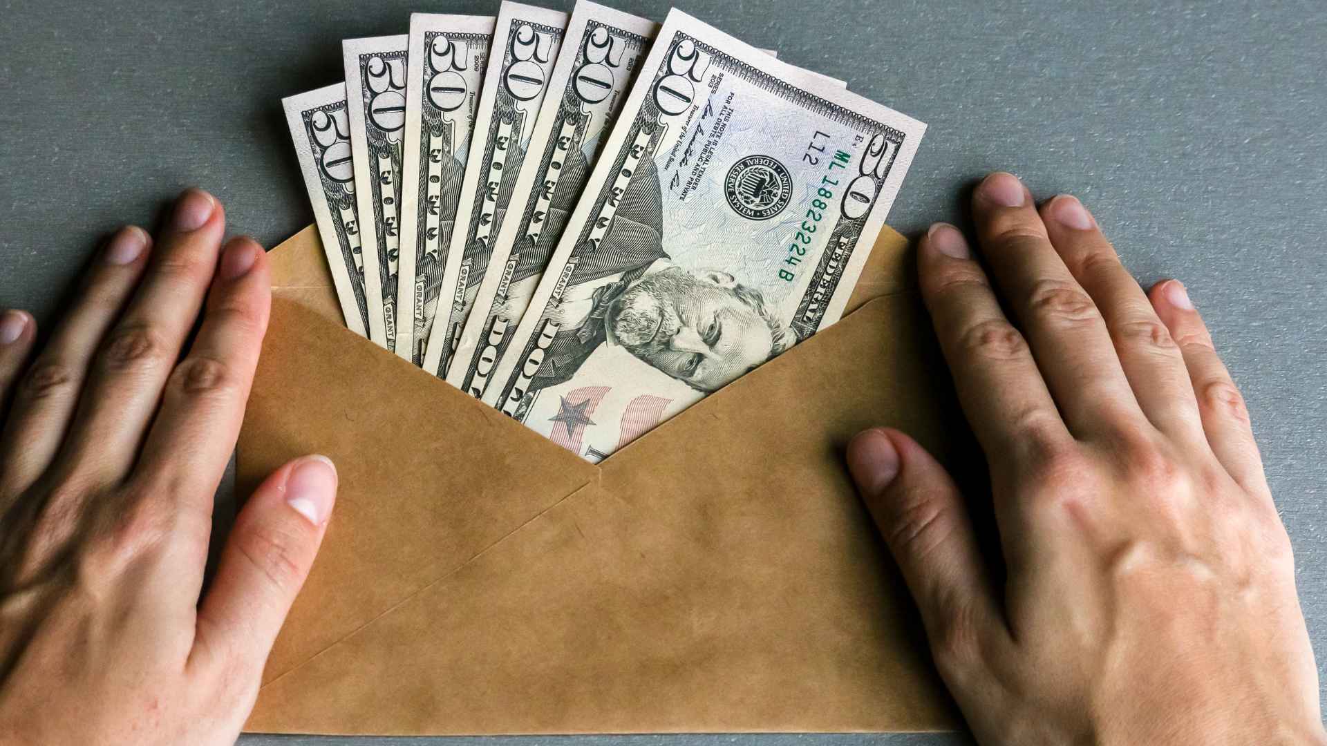 Envelope packed with $50 bills representing Sacramento’s $725 Family First monthly payments set to start in June.