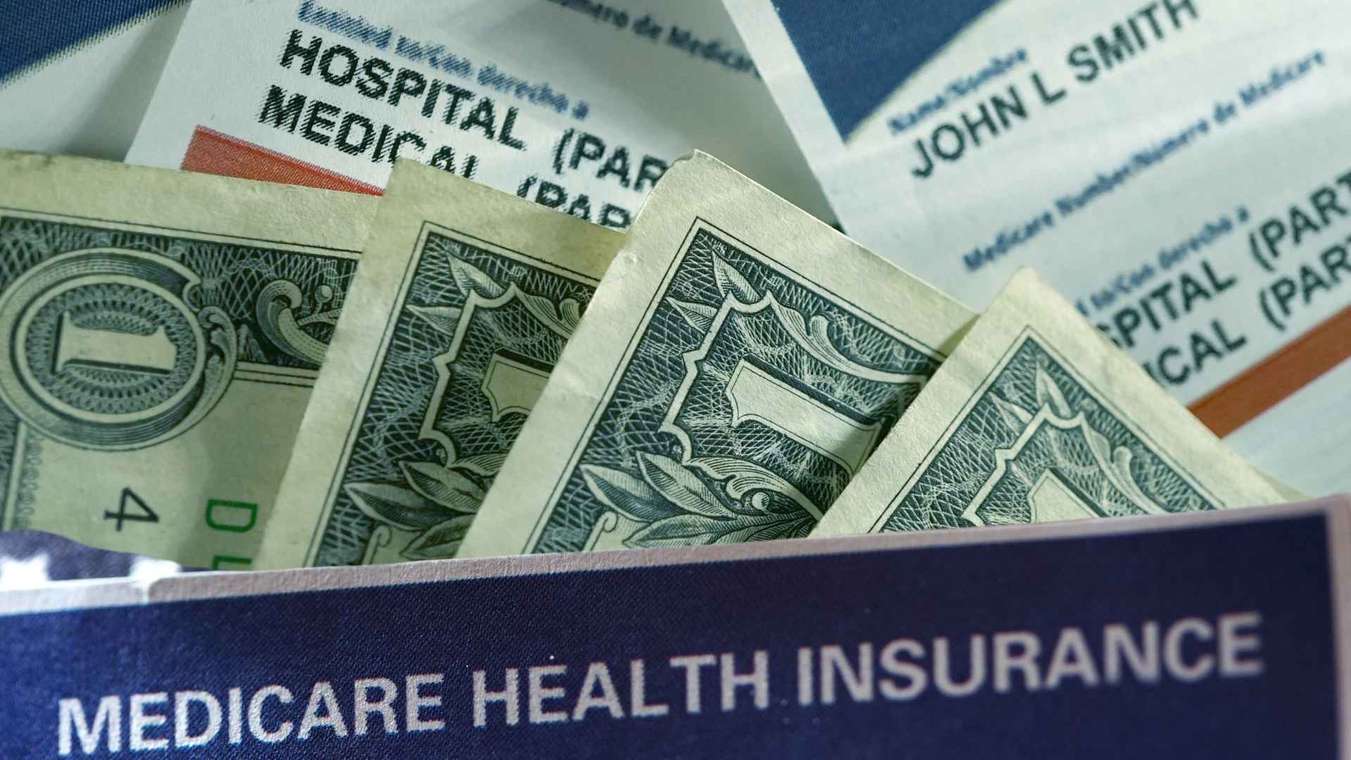Medicare health insurance card with dollar bills, symbolizing upcoming benefit cuts and funding shortfalls by 2033–2034