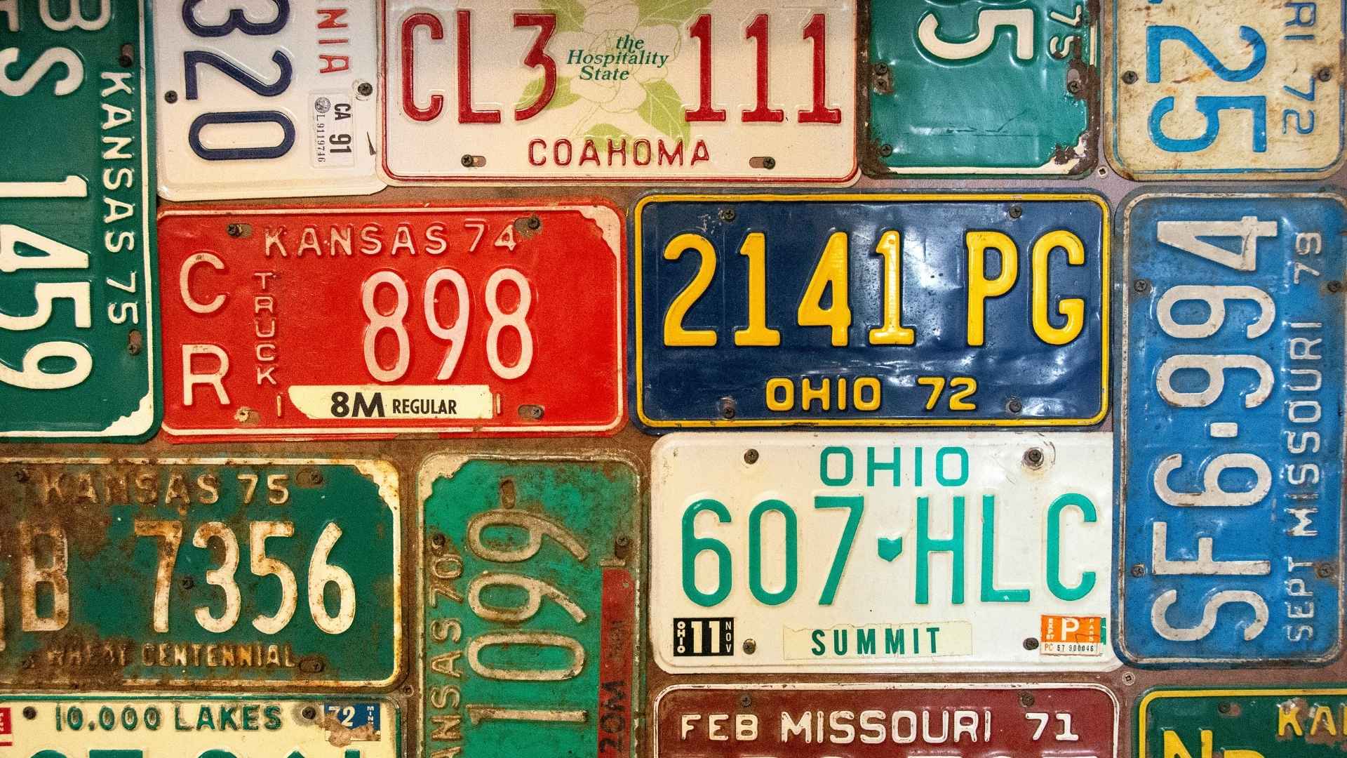 Vintage license plates from various U.S. states, highlighting changes in vehicle identification laws like Texas' new July 1 metal plate rule