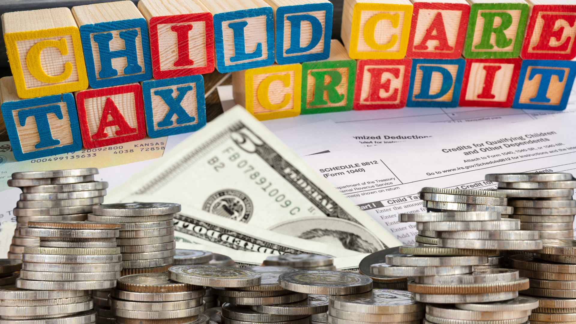 Colorful blocks spelling child care tax credit with money and IRS tax forms in background