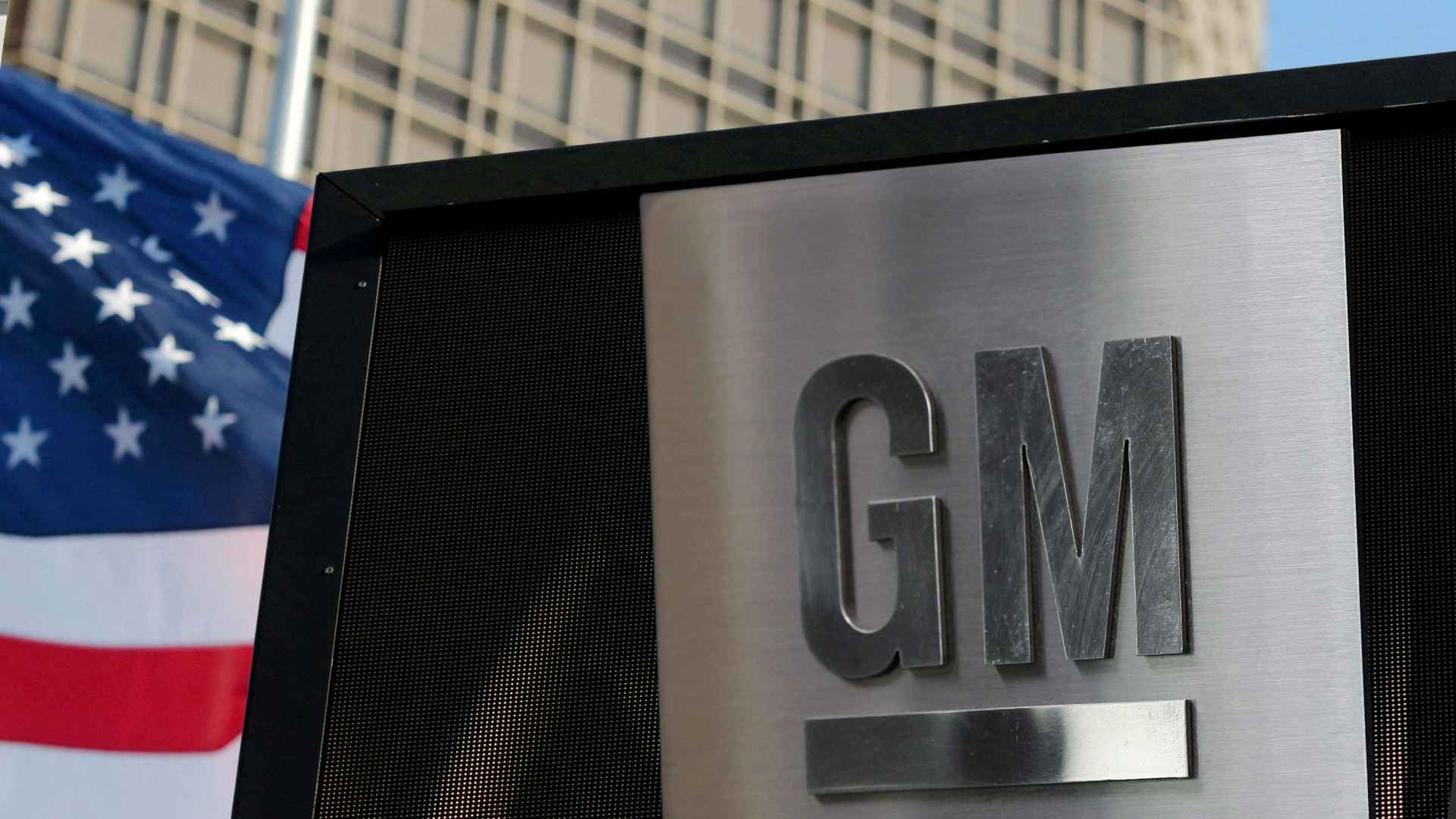 General Motors logo displayed on building sign with American flag in background