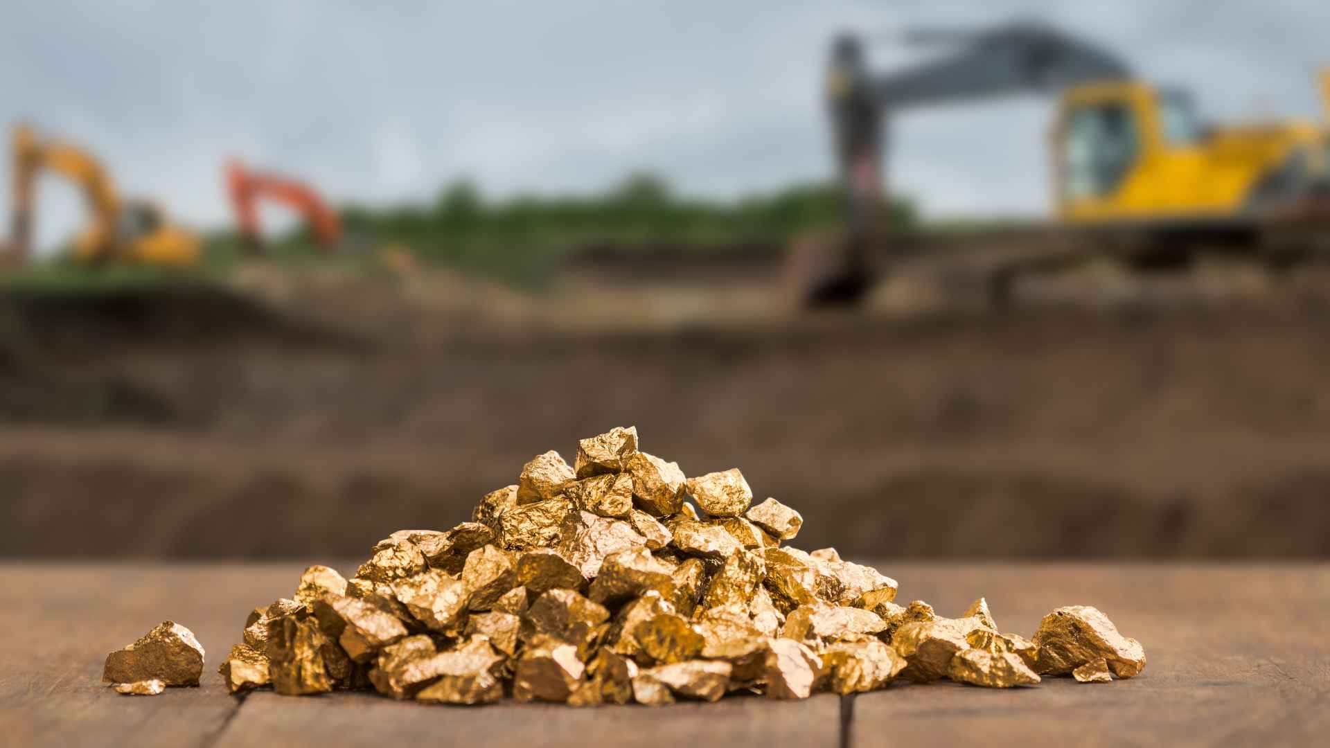 Pile of gold nuggets with mining machinery in background illustrating huge gold discovery in Chinese mine