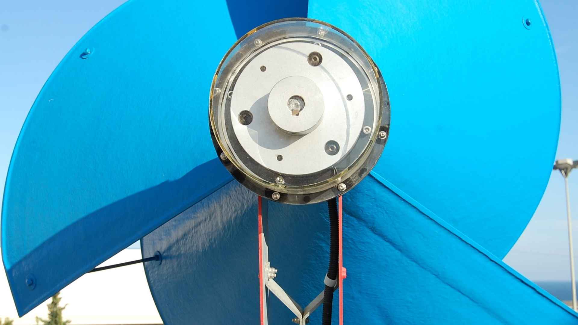 Close-up of LIAM F1 silent rooftop wind turbine with blue helical blades against clear sky