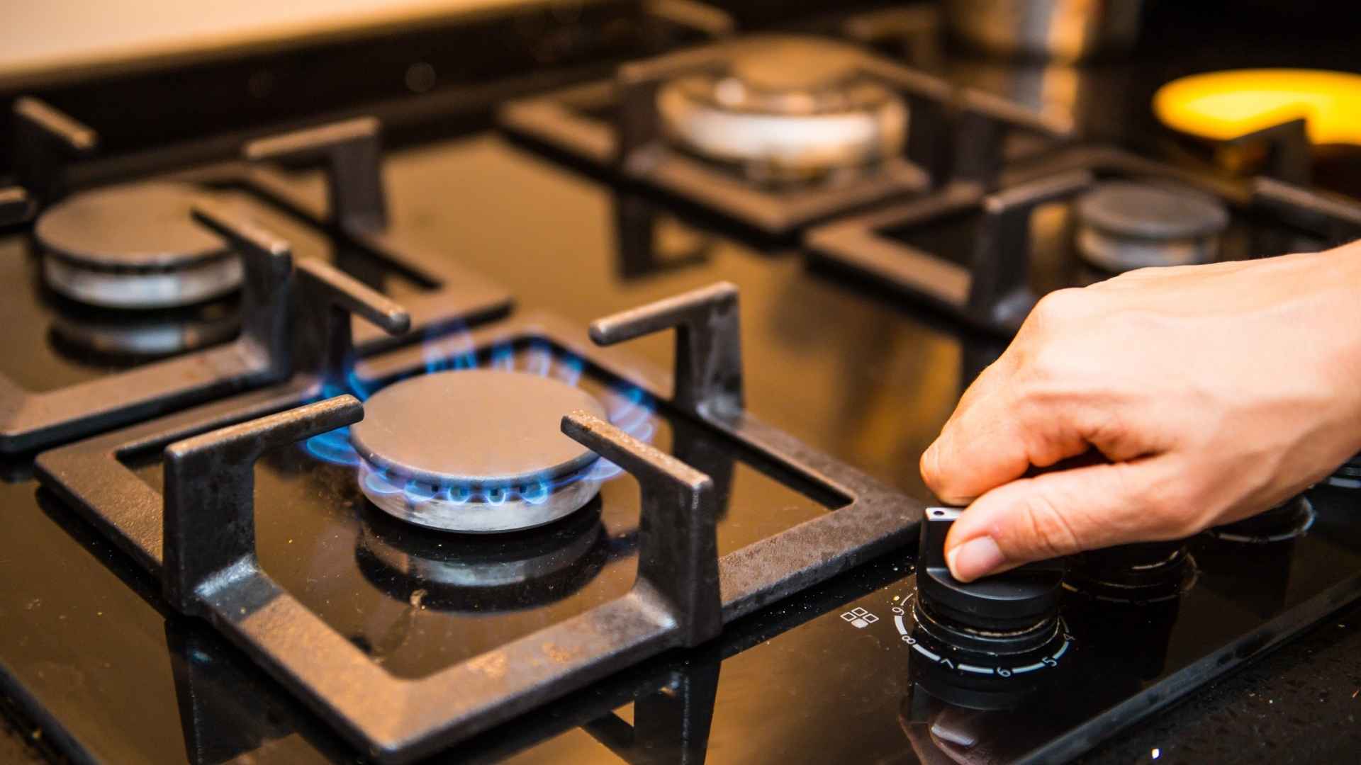 Person turning on gas stove burner affected by Southern California AQMD appliance ban