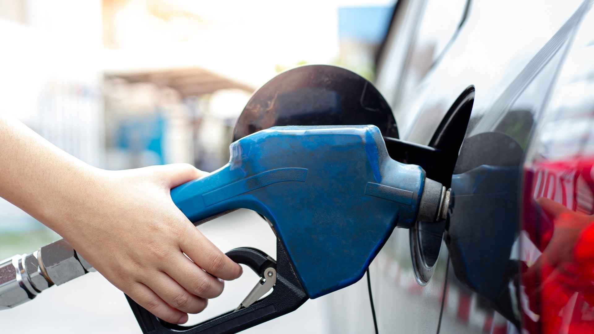 Person refueling a car at a gas station during lowest US summer gas prices in four years