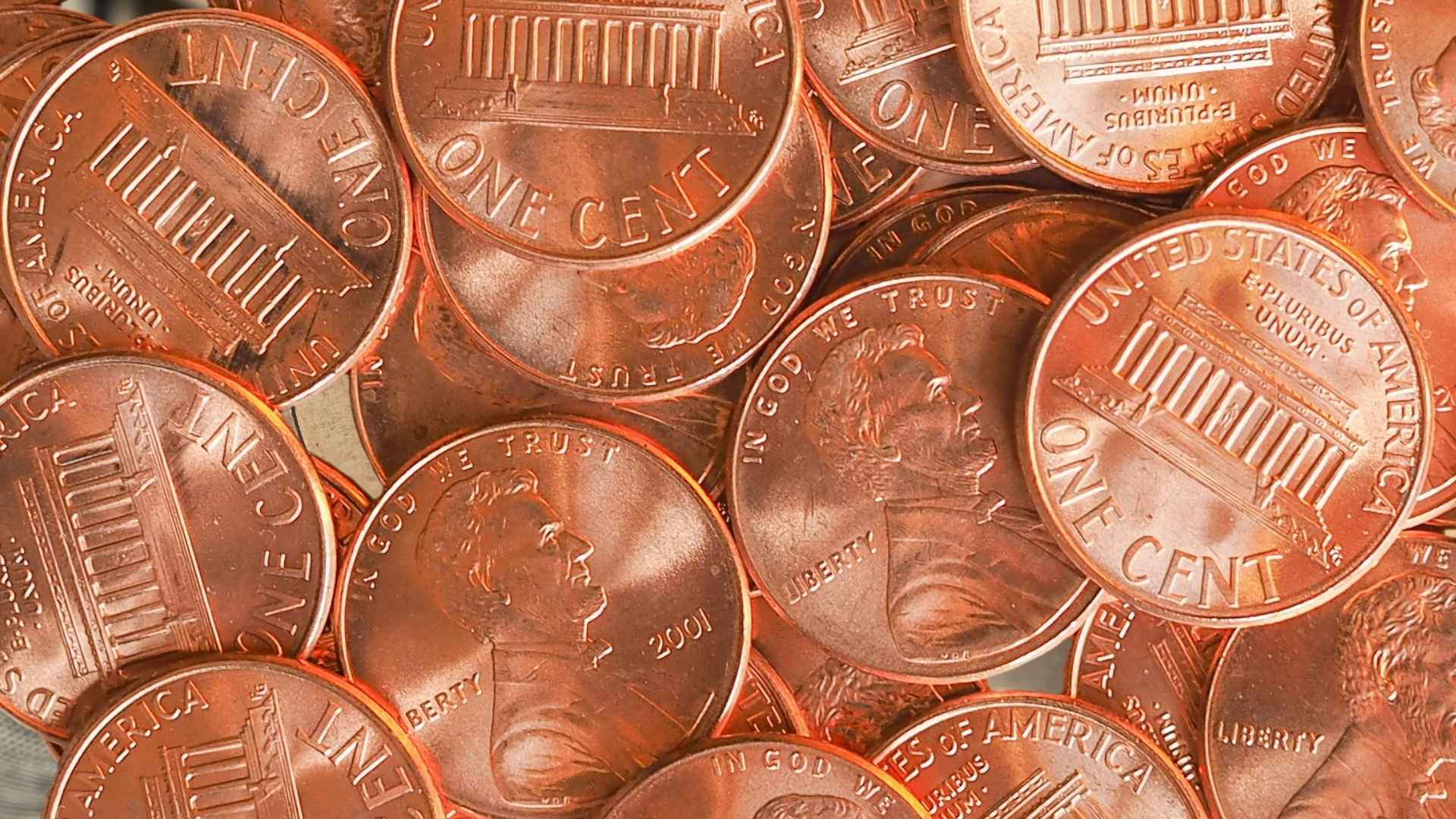 Close-up of multiple shiny U.S. one-cent coins as Congress moves to end penny production