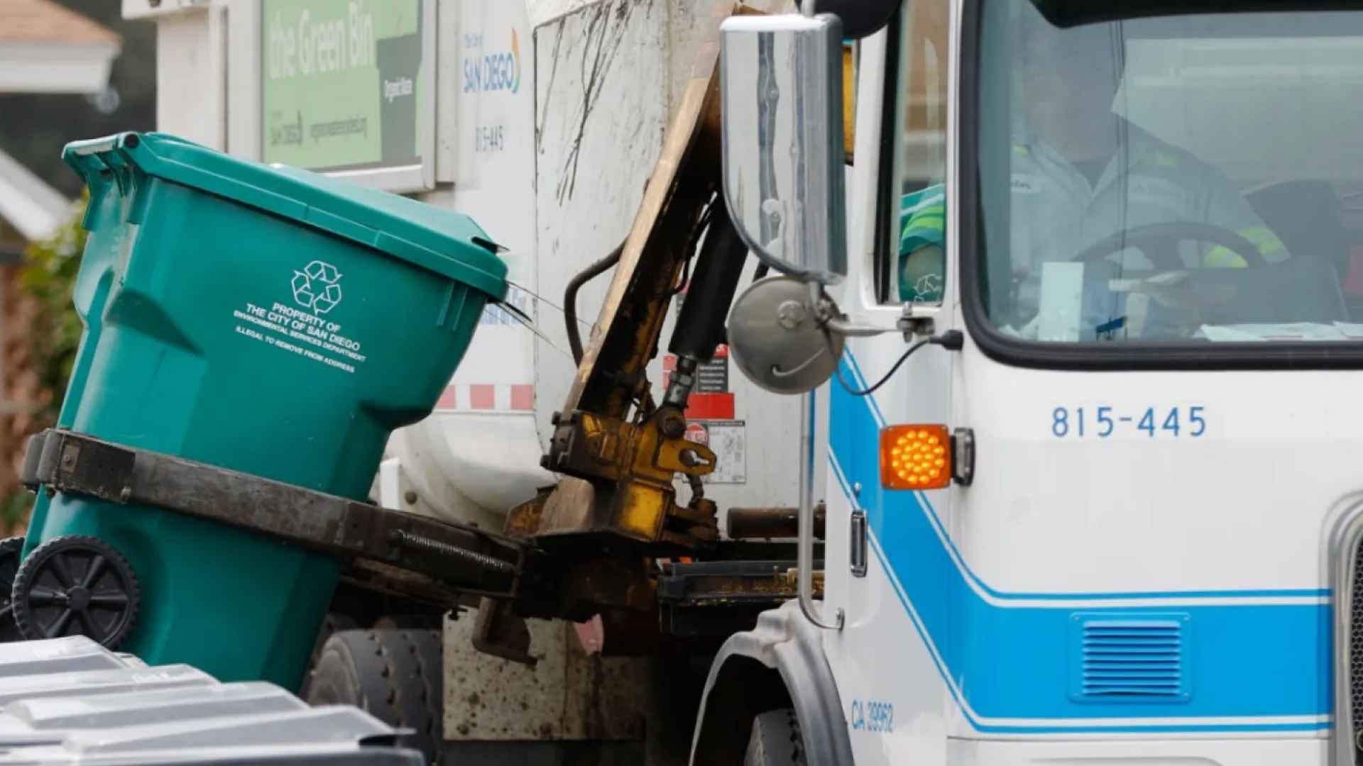 San Diego city garbage truck collecting recycling bin from residential street after end of free trash service