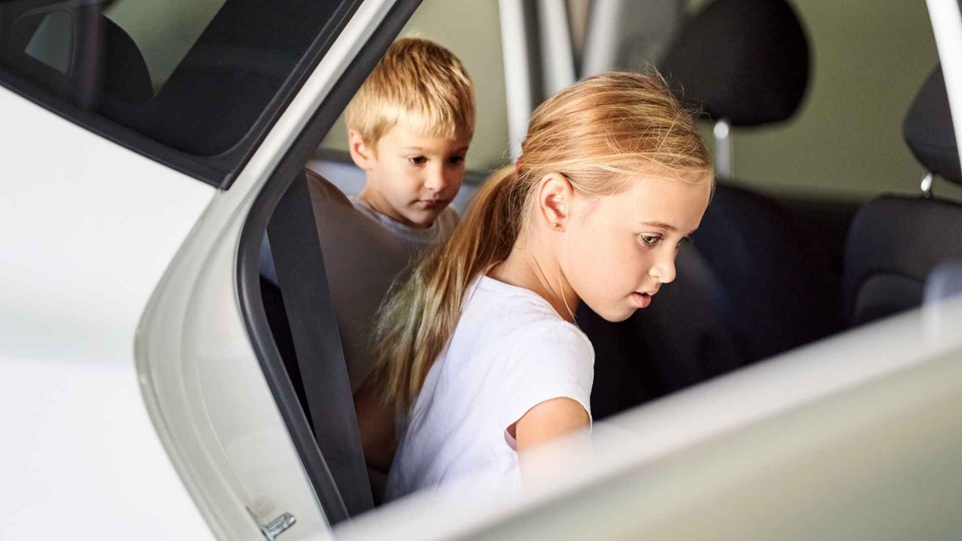 Two children getting into car backseat safety check