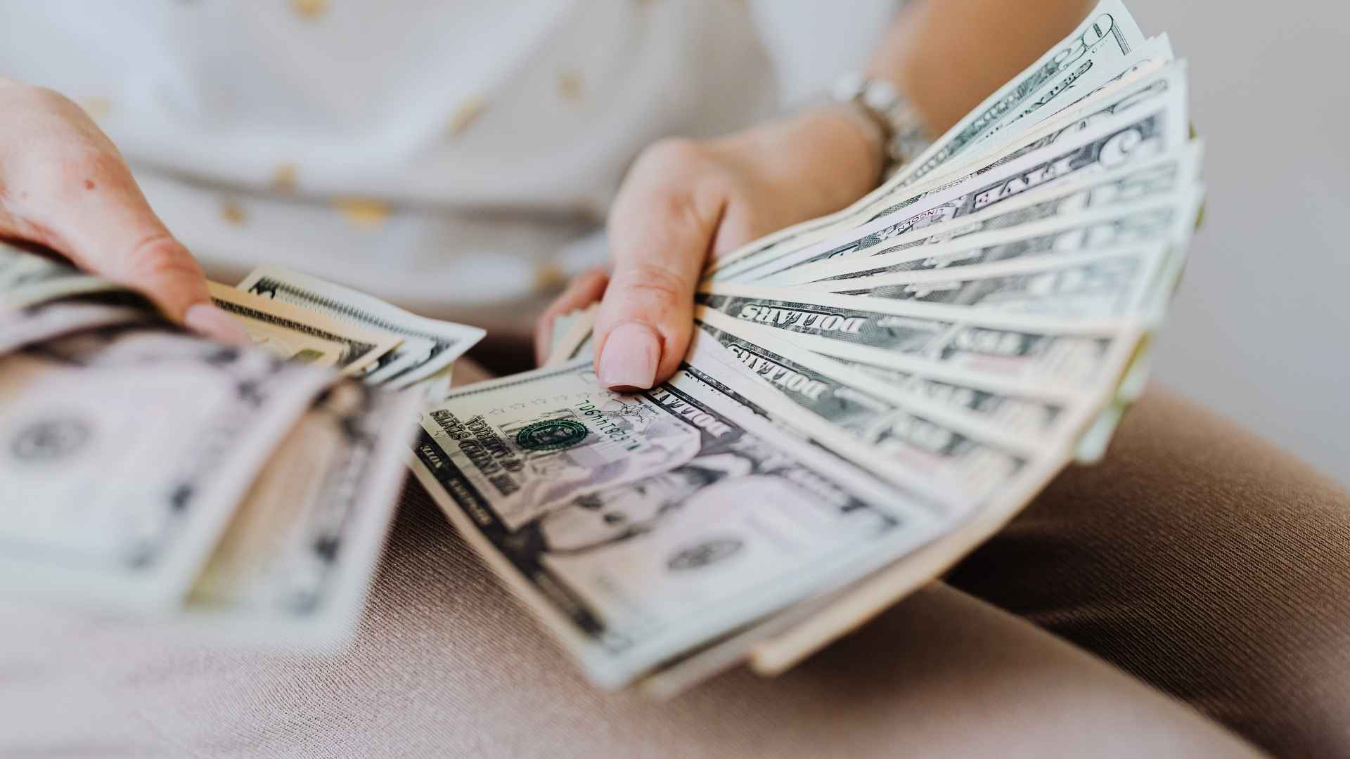 Person holding multiple U.S. dollar bills, illustrating SSDI benefit payments in August 2025