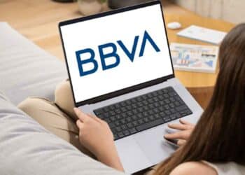 Mujer usando un portátil con el logo de BBVA en pantalla, representando oportunidades de empleo remoto e híbrido en BBVA.