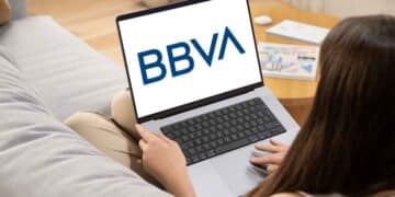 Mujer usando un portátil con el logo de BBVA en pantalla, representando oportunidades de empleo remoto e híbrido en BBVA.