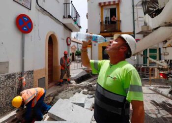 Obreros en una obra urbana, con uno de ellos bebiendo agua bajo el calor. Imagen representativa del sector de la construcción y las ofertas de empleo de Elecnor.