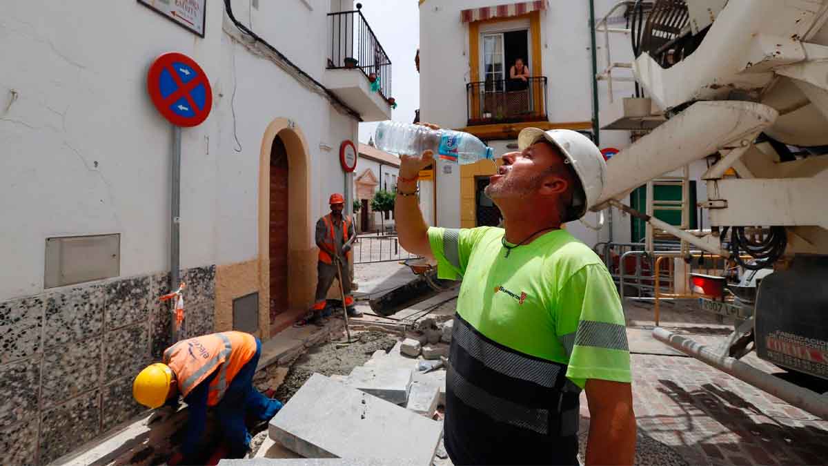 Obreros en una obra urbana, con uno de ellos bebiendo agua bajo el calor. Imagen representativa del sector de la construcción y las ofertas de empleo de Elecnor.