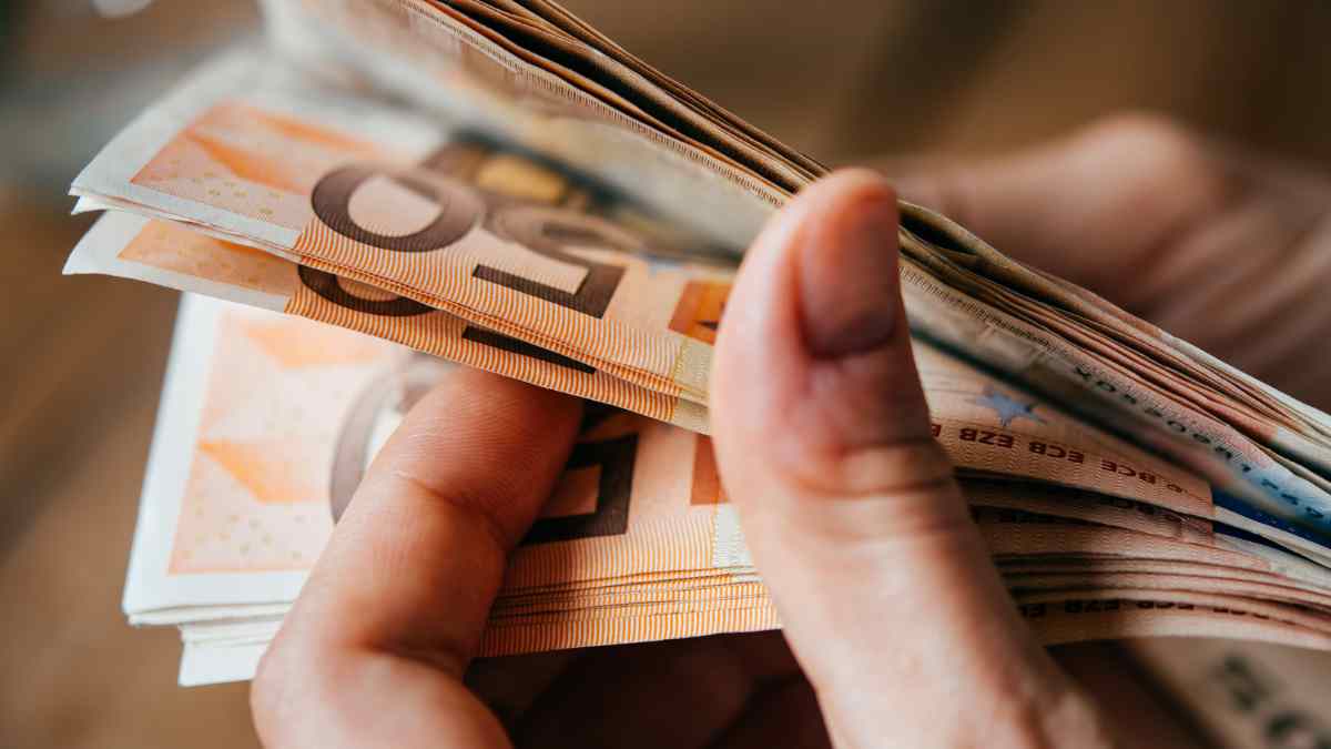 Persona contando billetes de euro, simbolizando el Ingreso Mínimo Vital 2025 y el extra de 115 euros.