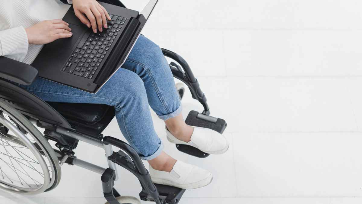 trabajador en silla de ruedas con portátil símbolo adaptación de puesto incapacidad permanente