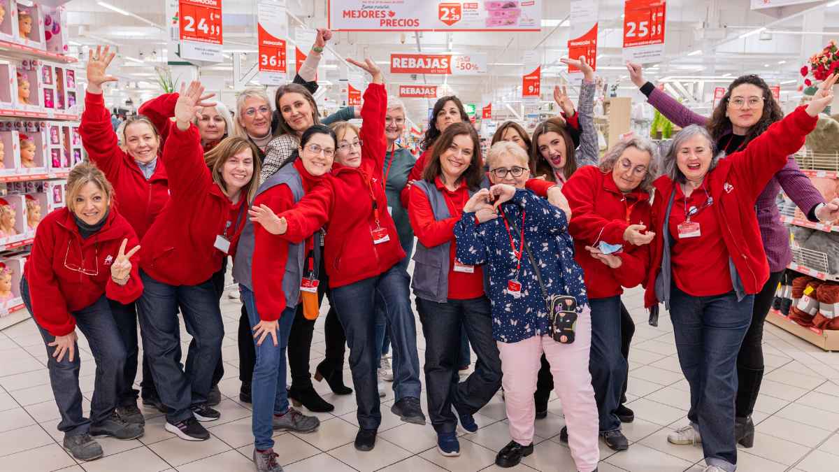 Empleados de Alcampo en un supermercado, con uniformes rojos, posan sonrientes ante la cámara