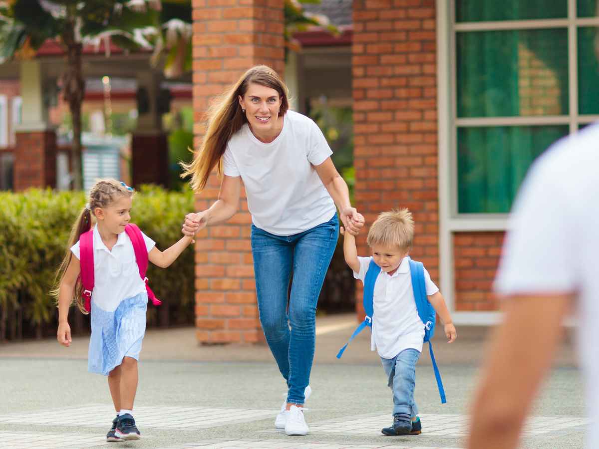Madre trabajadora con dos hijos pequeños saliendo del colegio, representando la conciliación laboral y la adaptación de jornada.