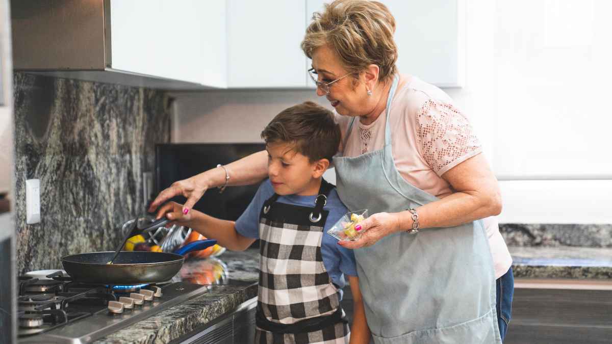 Mujer mayor cocinando con su nieto, representando la ayuda de 564 euros al mes para amas de casa