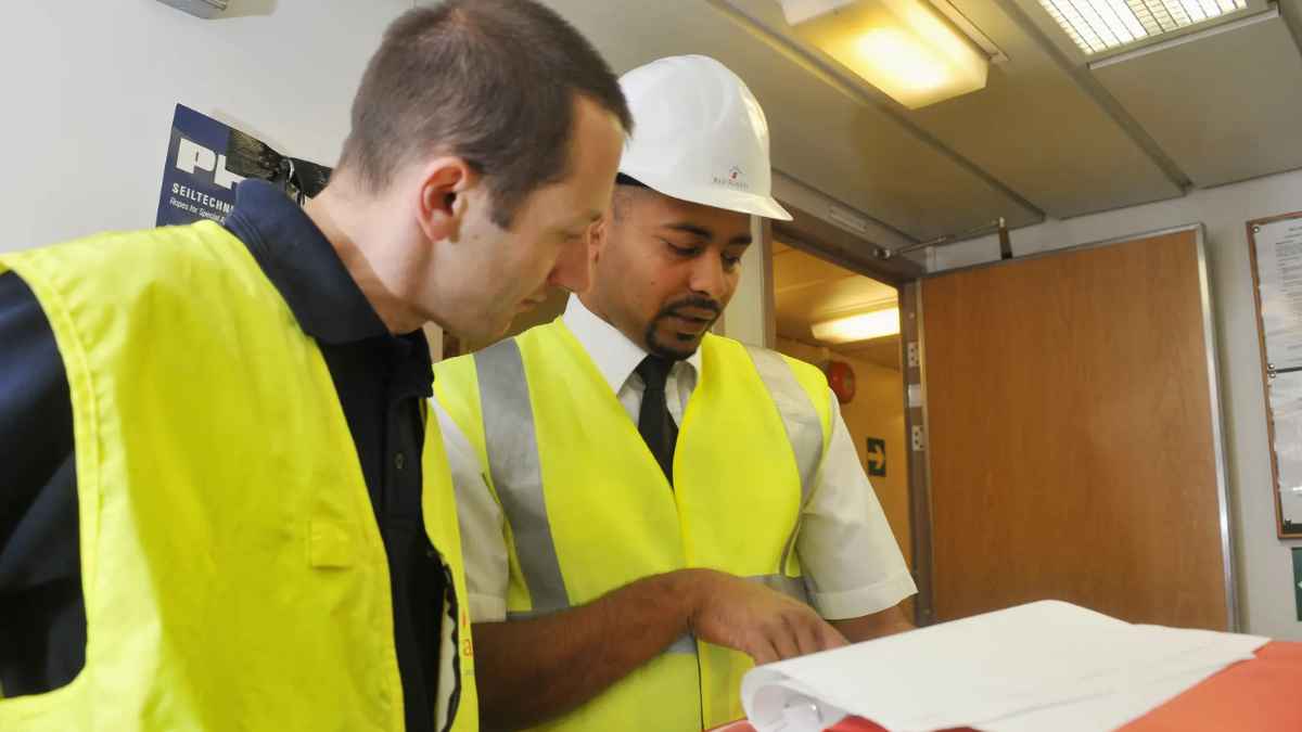Dos trabajadores con chalecos de seguridad revisando documentación en una inspección laboral