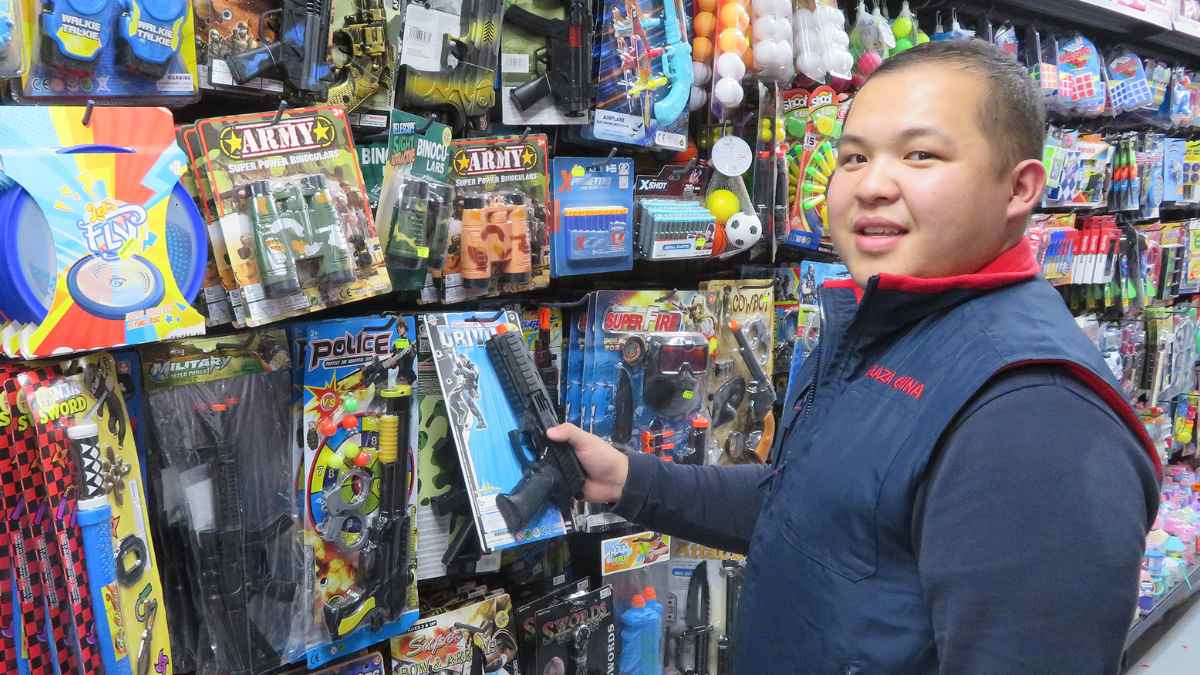 Comerciante chino en un bazar de Mallorca mostrando productos de juguetería, ilustrando la situación actual de cierres puntuales