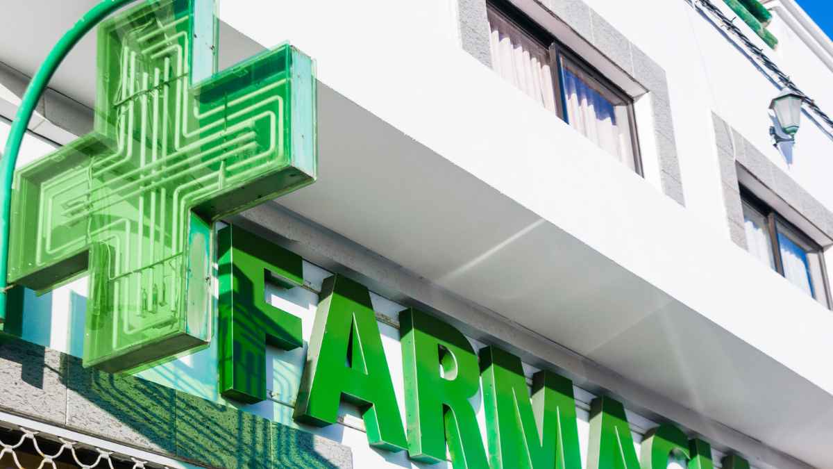 Fachada de farmacia con la cruz verde luminosa en primer plano