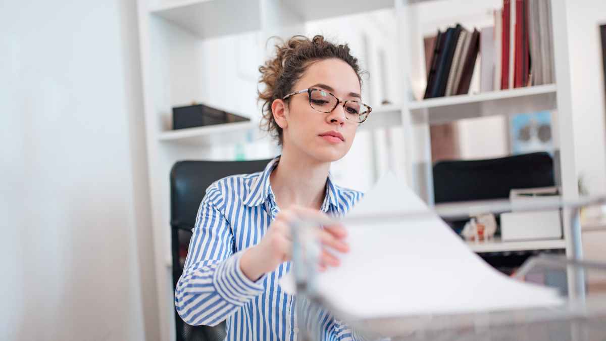 Auxiliar administrativo recogiendo documentos de la oficina
