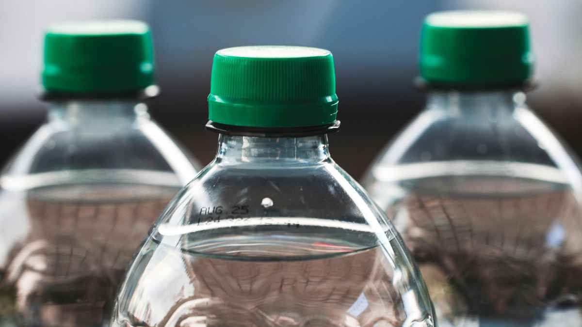 Primer plano de botellas PET con tapón fijo verde cambio normativo 2025