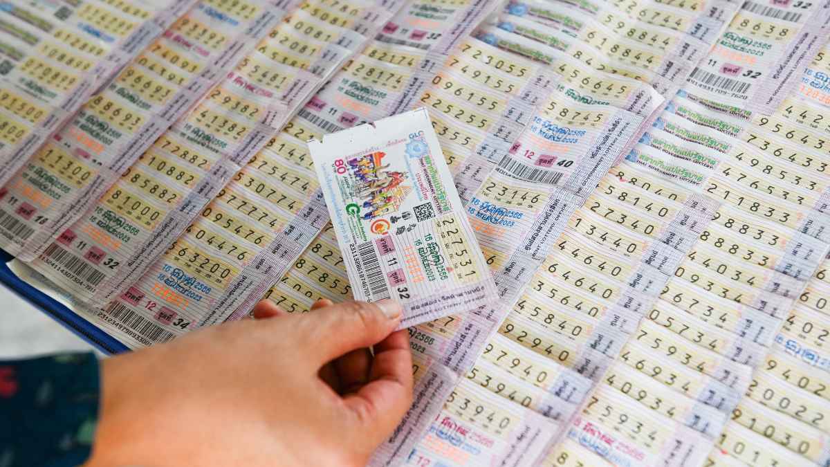 Mano sosteniendo un décimo de lotería entre varios boletos