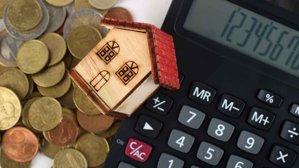 Casa de madera sobre calculadora y monedas que representan la deducción del seguro de hogar en la declaración de la Renta 2024
