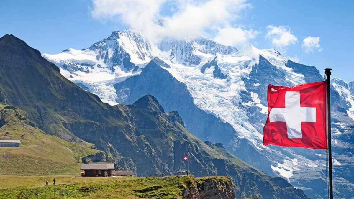 Paisaje de los Alpes con bandera de Suiza, ejemplo de oportunidades y mejor calidad de vida para un español en Suiza