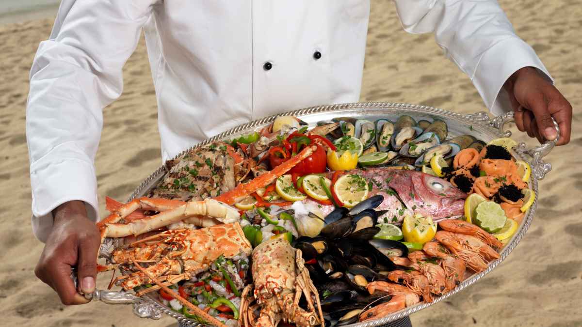Camarero sostiene una bandeja con festín de marisco y pescado fresco valorado en 400 euros en Il Cortigiano, Bari